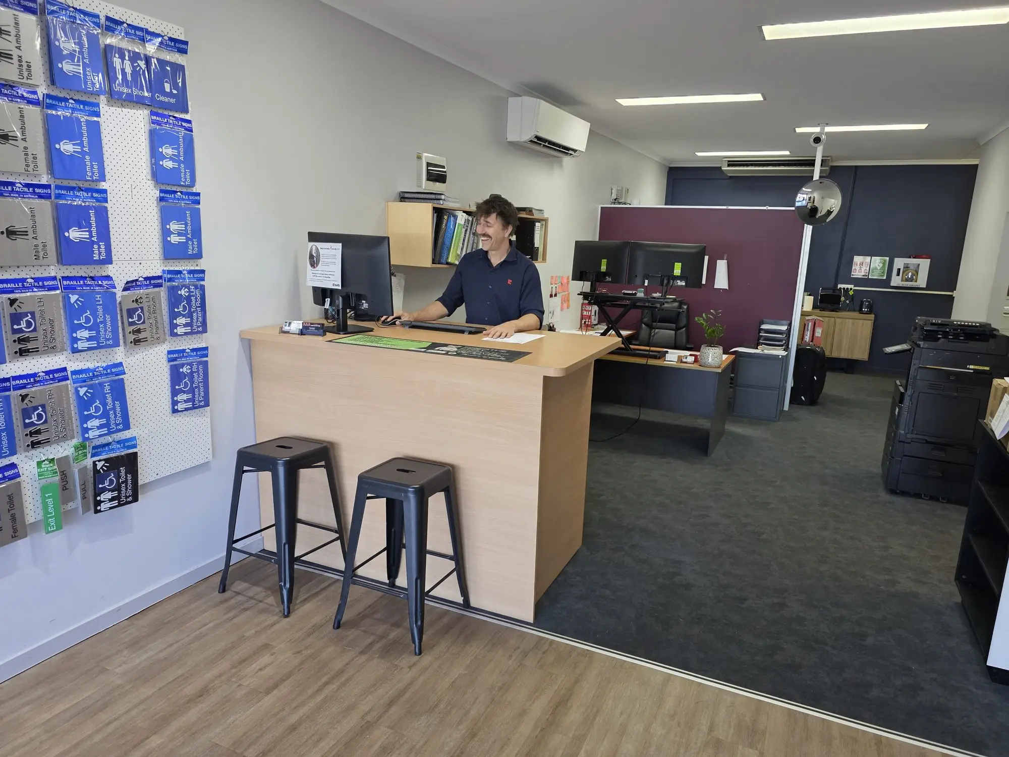 The Bretts PHD front counter, beside a wall of braille and tactile washroom signs.