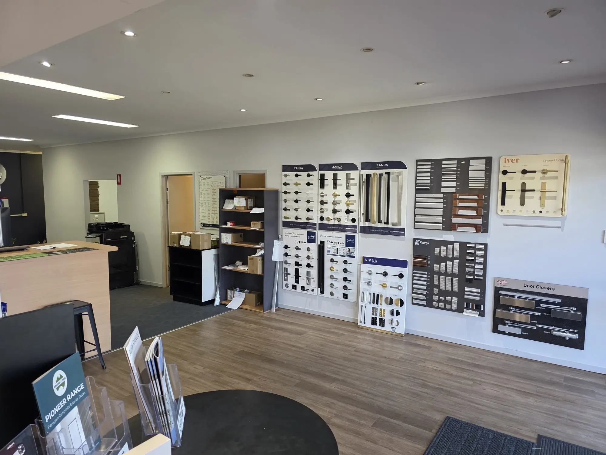 Door handle, lever, pull handle and door closer display boards along the showroom wall.